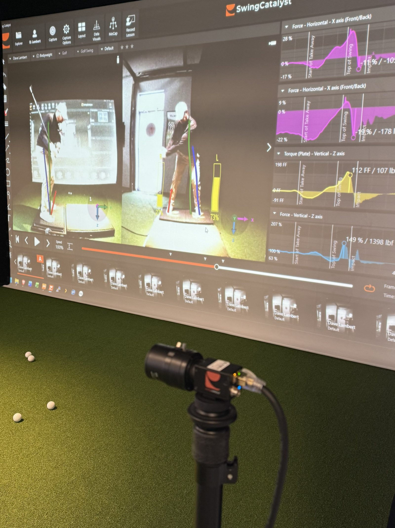 Dave Lambert kneeling beside a student, explaining Swing Catalyst force plate data on screen