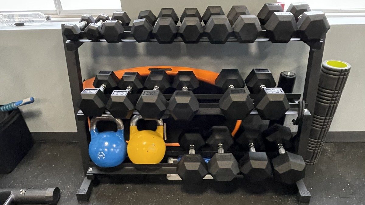 Fully equipped training gym — squat rack, bands, dumbbells — integrated with the coaching studio
